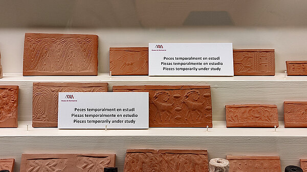 A shelf with modern roll-outs of seals. Some show ibexes others floral patterns. Some pieces are missing.