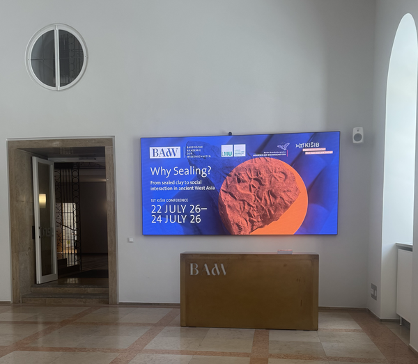 The foyer of the Bavarian Academy of Sciences and Humanities in the Residence of Munich showing the poster of the conference on a screen.