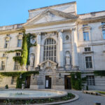 A minumental entrance to the State Library Berlin with a fountain in front.