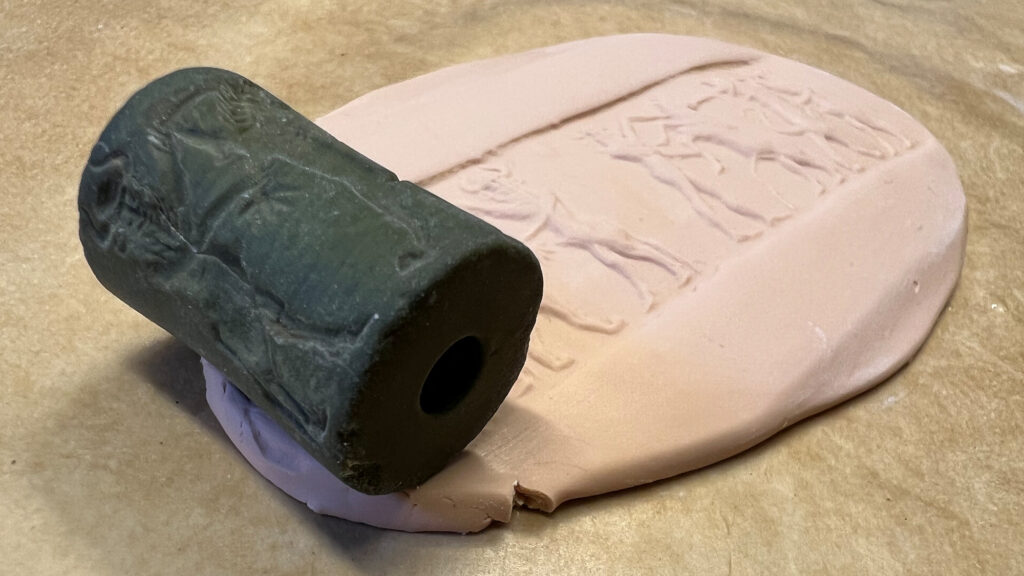 A cylinderseal rolled out on a mass of Fimo, showing the impression, the seal made.