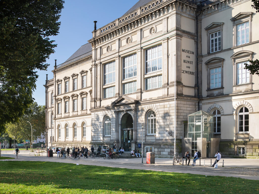 A view on the museum. Many people are in front of the museum, which is housed in an impressive high building.