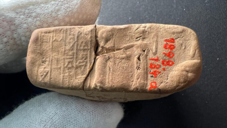 A close-up of a sealed envelope with visible cuneiform script and two figures. The right one is leading the left one to the right.